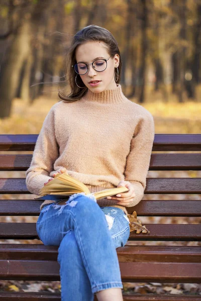 Krásná Mladá Dívka Knihou Sedí Lavičce Podzimním Parku — Stock fotografie