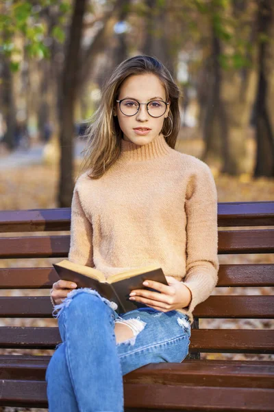 Piękna Młoda Dziewczyna Książką Siedzi Ławce Jesiennym Parku — Zdjęcie stockowe