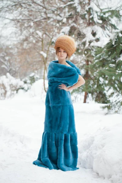 年轻漂亮的女孩在毛皮帽子和红色狐狸毛皮大衣摆在冬季公园背景 — 图库照片