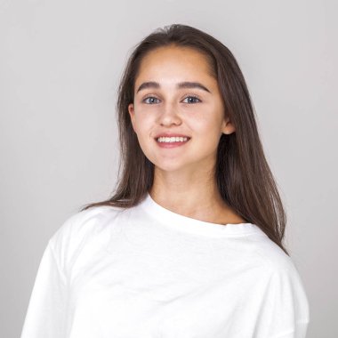 Gri arka planda soyutlanmış, güzel, mutlu, esmer bir kadının portresi.