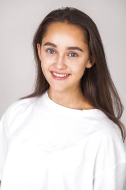 Gri arka planda soyutlanmış, güzel, mutlu, esmer bir kadının portresi.