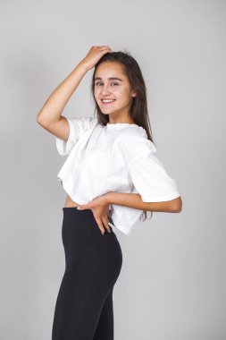 Gri arka planda soyutlanmış, güzel, mutlu, esmer bir kadının portresi.