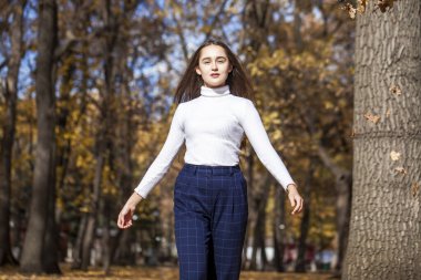 Güz parkında genç ve güzel bir esmer kadının portresi.