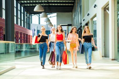 Genç kız arkadaşlar alışveriş merkezinde geziyorlar.