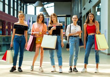 Mutlu genç kız arkadaşlar alışveriş merkezinde yürüyor.