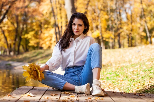 秋の公園でポーズをとっている青いジーンズの少女の完全な長さの肖像 — ストック写真