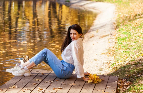 秋の公園でポーズをとっている青いジーンズの少女の完全な長さの肖像 — ストック写真