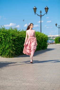 Pembe elbiseli güzel esmer bir kadının tam boy portresi.