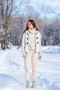 Kış parkında poz veren güzel bir kızın tam boy portresi.