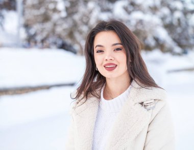 Kış parkında genç ve güzel bir esmer kadının portresi.