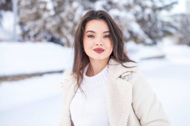 Kış parkında genç ve güzel bir esmer kadının portresi.