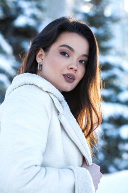 Kış parkında genç ve güzel bir esmer kadının portresi.