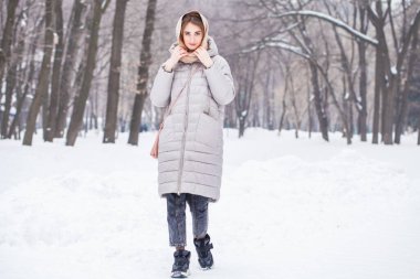 Kış parkında poz veren güzel bir kızın tam boy portresi.