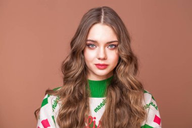 Bej arka planda genç ve güzel bir kızın stüdyo portresi.