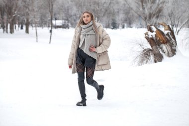 Kış parkında poz veren güzel bir kızın tam boy portresi.