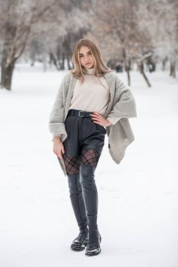 Kış parkında poz veren güzel bir kızın tam boy portresi.