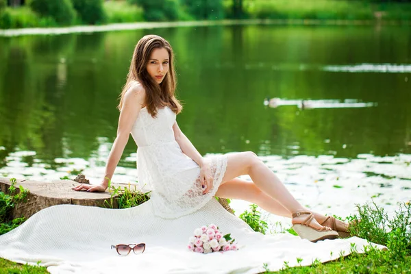 若いブルネットの女性は湖 夏の公園の屋外でピクニックに座っていた — ストック写真