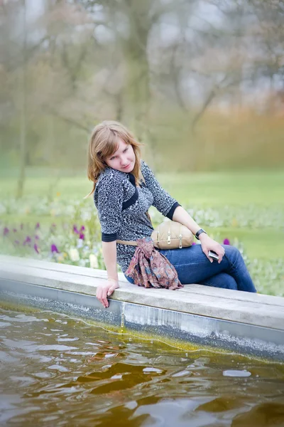 Jonge romantische vrouw zitten in de buurt van de vijver — Stockfoto