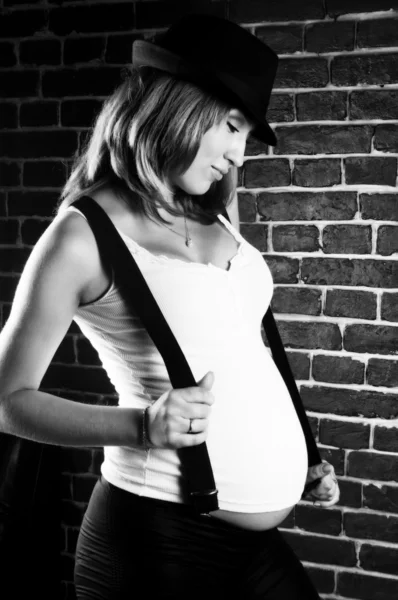 Pregnant woman with suspenders and hat — Stock Photo, Image