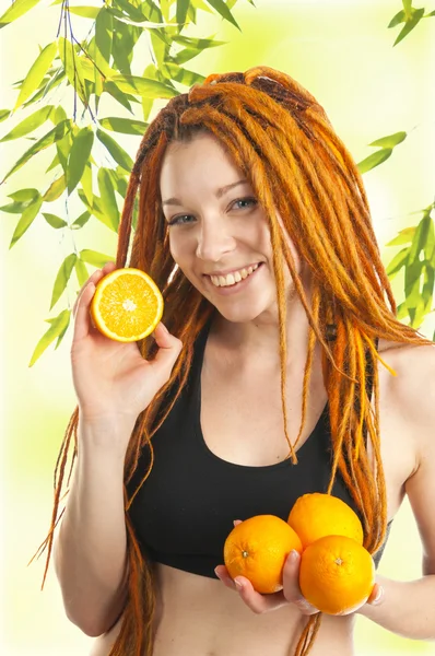 Schönes Mädchen mit roten Dreadlocks und Orangen in den Händen — Stockfoto