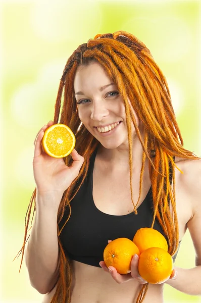 Schönes Mädchen mit roten Dreadlocks und Orangen in den Händen — Stockfoto