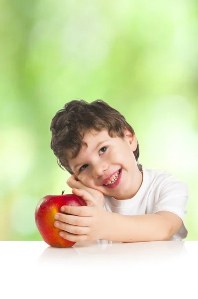 Lilla leende pojke med ett rött äpple — Stockfoto