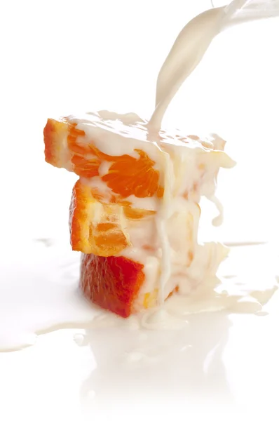 Oranje segmenten met spatten melk — Stockfoto
