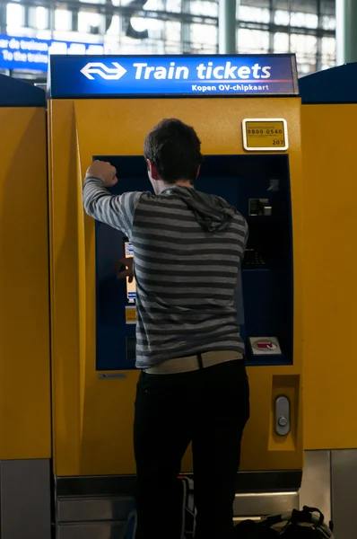 Człowiek Kupując bilety kolejowe na lotnisku amsterdam — Zdjęcie stockowe