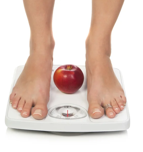 Female feet on scales with apple — Stock Photo, Image
