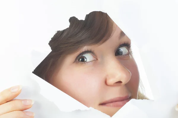 Curious beautiful woman looking through the hole in paper — Stock Photo, Image