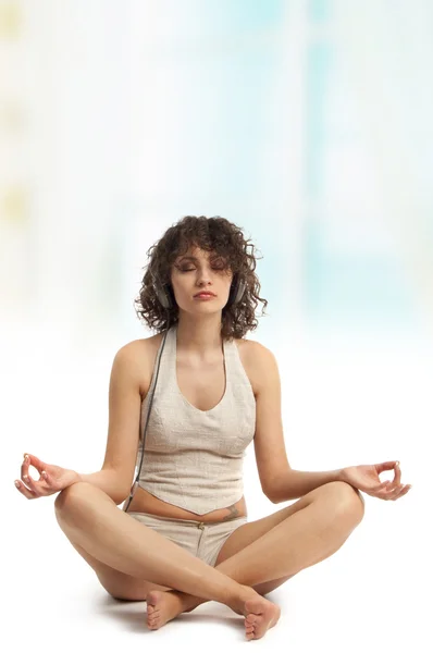 Mulher encaracolada meditando com música — Fotografia de Stock