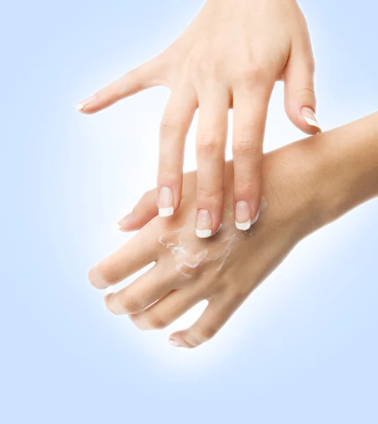 Hermosas manos femeninas aplicando crema — Foto de Stock