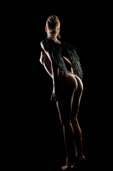 Nude beautiful woman with black wings isolated on black background