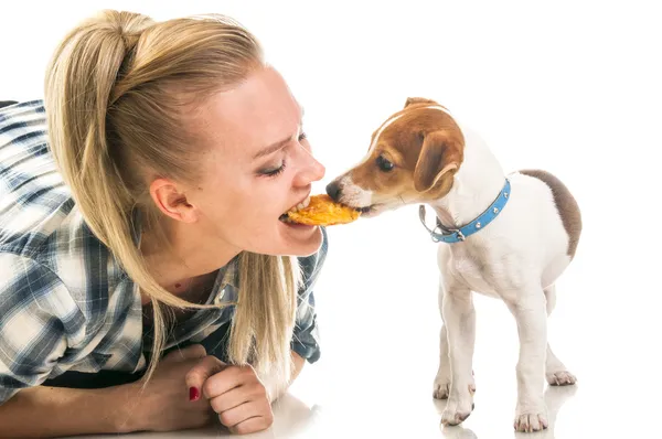 Woman eatting biscuit with puppy — Stock Photo, Image