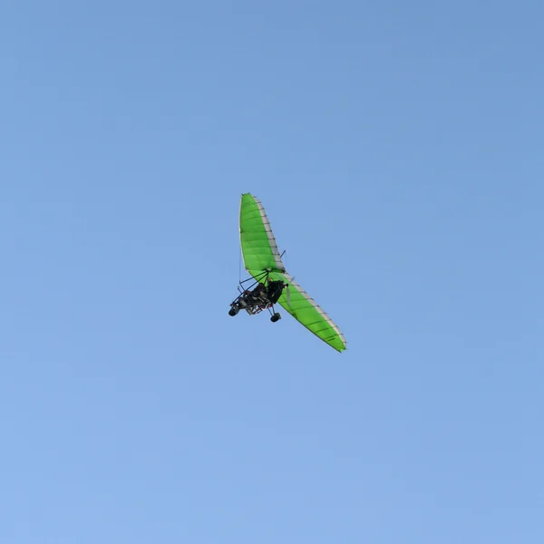 Groene motor hangen-zweefvliegtuig in een heldere blauwe hemel — Stockfoto