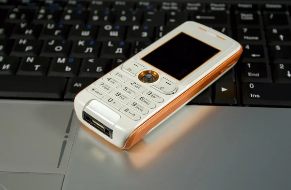 Telefono cellulare su un computer portatile — Foto Stock