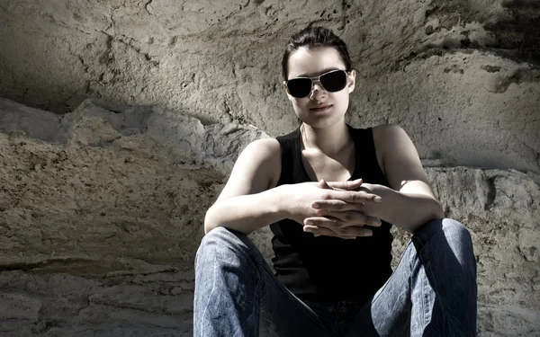 Model sitting on the rocks. Urban style — Stock Photo, Image