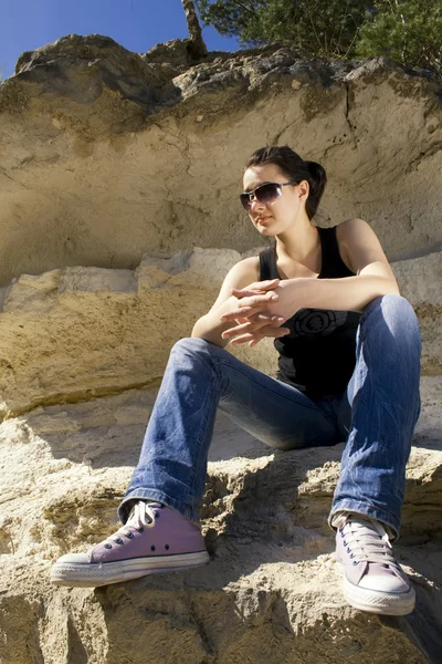 Model sitting on the rocks. Urban style — Stock Photo, Image