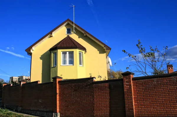 Žlutý dům mezi modrá obloha — Stock fotografie