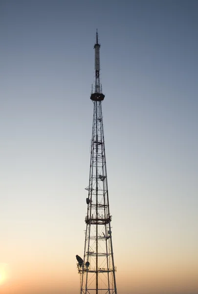 Torre di comunicazione al tramonto con paesaggio urbano — Foto Stock