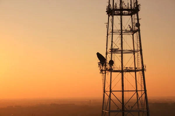 Komunikační věž při západu slunce s městskou krajinou — Stock fotografie