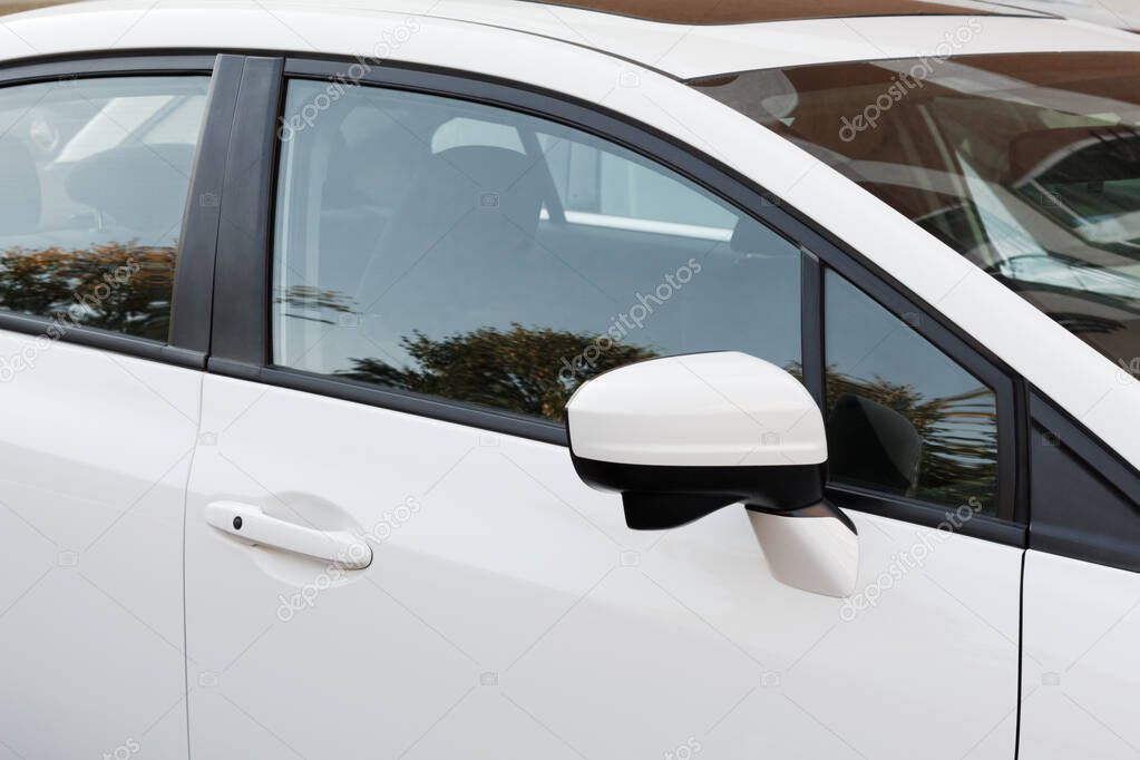 Side rear-view mirror on a white modern car. Close-up car details