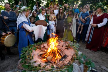 Vilnius, Litvanya, 24 Haziran 2022. Litvanya 'nın Vilnius kentindeki Verkiai Park' ta düzenlenen yaz ortası kutlamaları sırasında, yaz ortası festivali (Jonins veya John 's Day) Litvanya ulusal kostümlü kadınlar taze çavdar ekmeği ile ayinler düzenlerler..