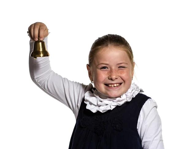 Zwinkernde junge Schulmädchen, die eine goldene Glocke auf weißem Backgro läutet — Stockfoto