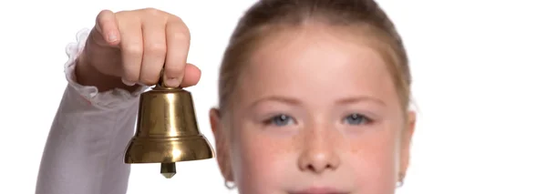 Молодая школьница звонит в золотой колокол на белом фоне — стоковое фото
