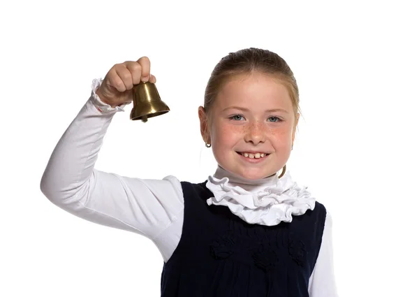Winking Young school girl ringing a golden bell on white backgro — Stock Photo, Image