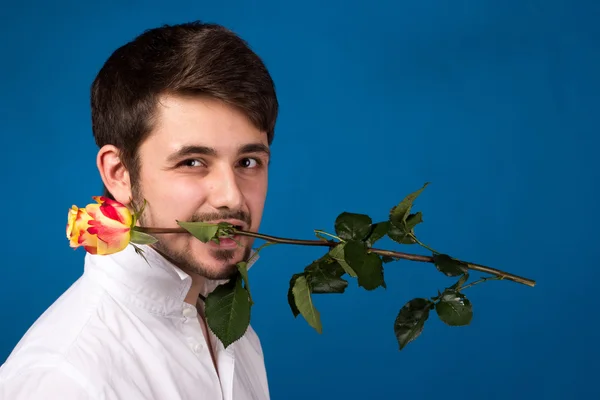 Joven sosteniendo una rosa roja en su boca — Foto de Stock