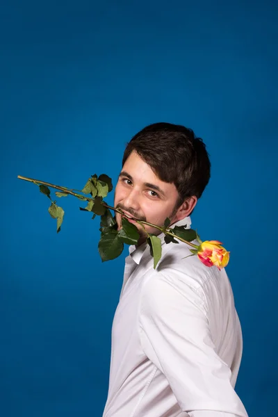 Joven sosteniendo una rosa roja en su boca — Foto de Stock