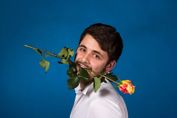 Giovane uomo con una rosa rossa in bocca — Foto Stock