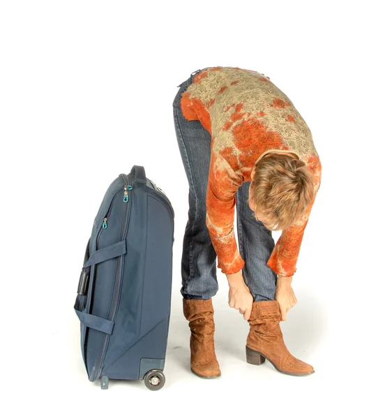 Frau korrigiert Stiefel in der Nähe eines Koffers — Stockfoto
